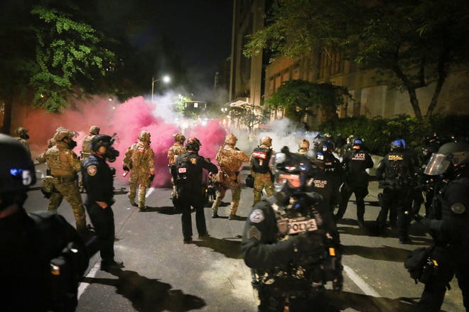 Police respond to protesters during a demonstration,  Friday, July 17, 2020 in Portland. Militarized federal agents deployed by the president to Portland, fired tear gas against protesters again overnight as the city's mayor demanded that the agents be removed and as the state's attorney general vowed to seek a restraining order against them.