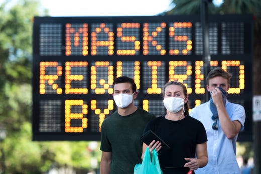 People wearing protective face masks walk along King St. on July 18, 2020 in Charleston, S.C.  South Carolina is struggling with a high percentage of positive coronavirus (COVID-19) test results.