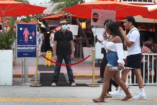 Juan Carlos, a host at Ocean 10 restaurant, stands at the entrance of the restaurant to turn customers away as a curfew from 8pm to 6am is put in place on July 18, 2020 in Miami Beach, Florida. The City of Miami Beach put the curfew back into place to fight the spread of the coronavirus (COVID-19), which has spiked in recent days after the reopening of businesses.