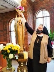 Sister Rosanne Marie Glaza crowns the statue of Our Lady on May 1 during a ceremony at the Presentation of the Blessed Virgin Mary Convent in Livonia.