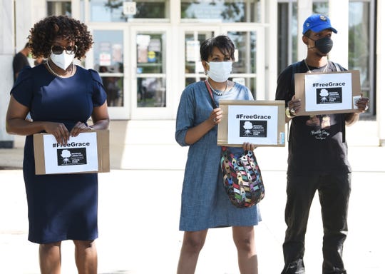 Tylene Henry, Monique Campbell and Raynard Lanier II hold signs in support for the release of "Grace" from juvenile detention outside a hearing for the girl on Monday, July 20, 2020.