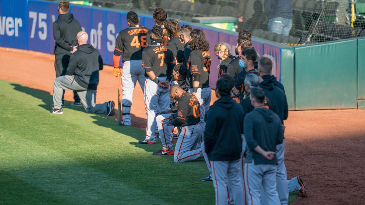Several members of the San Francisco Giants kneel before the national anthem before Monday's exhibition game against the Oakland Athletics.