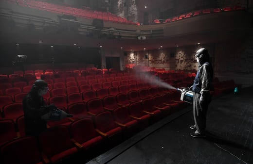 A South Korean worker wearing protective clothes sprays disinfectant in a theatre at Sejong Center in Seoul on July 21, 2020, amid the COVID-19 coronavirus pandemic.