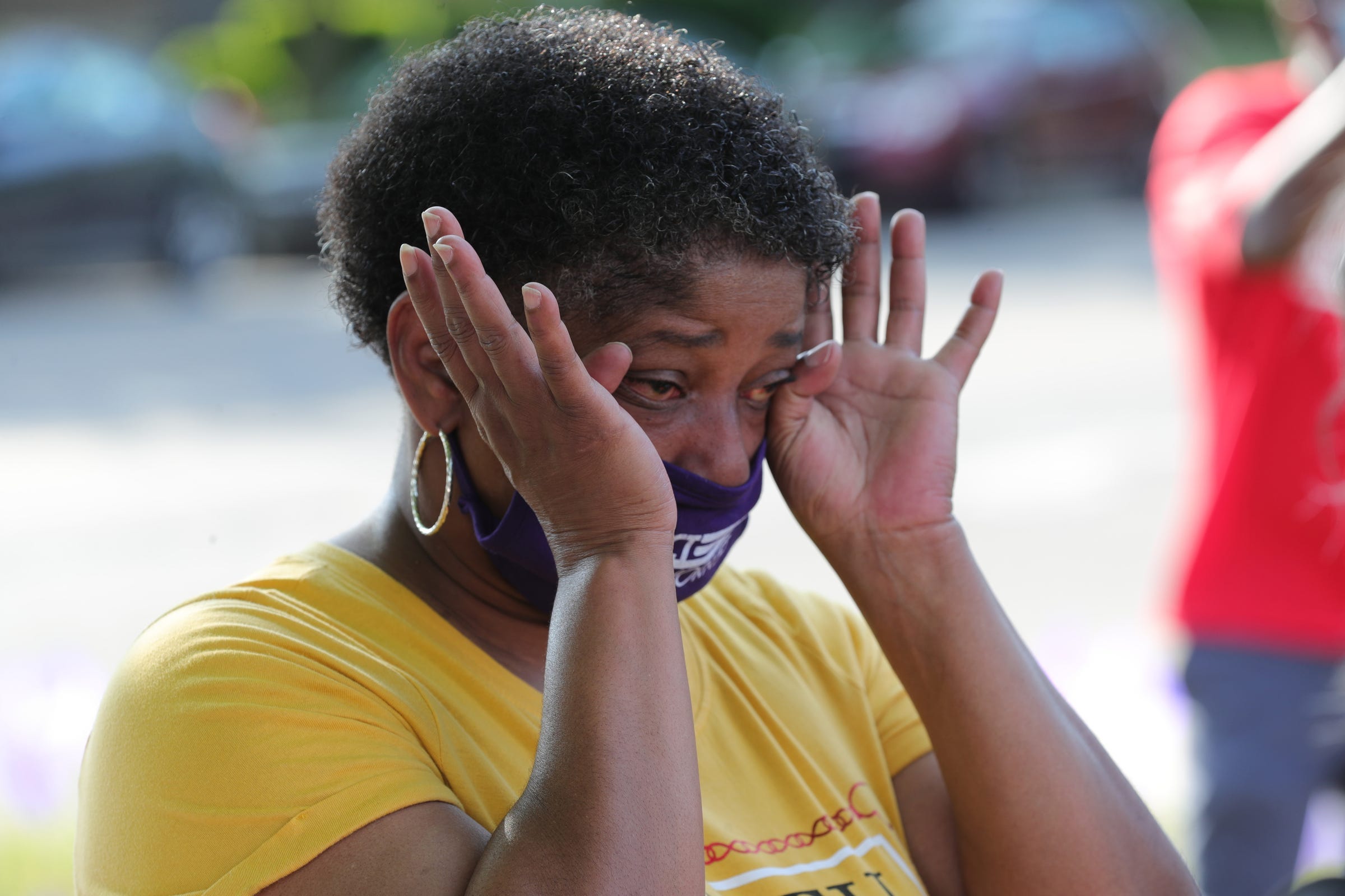 Terry Ells-berry wipes away tears during the program as Members of SEIU and community members gathered on East Grand Boulevard to pay respects nursing home residents staff members who died from the COVID-19 virus on June 19, 2020 in Detroit. 1,900 purple flags were placed at the site to represent those who passed from the virus on June 18, 2020. Kym Worthy the Wayne County prosecutor was in attendance listening to speakers.