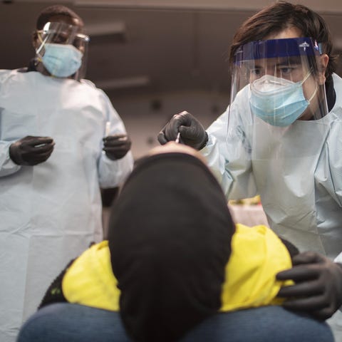 Health care workers use a nasal swab to test a per