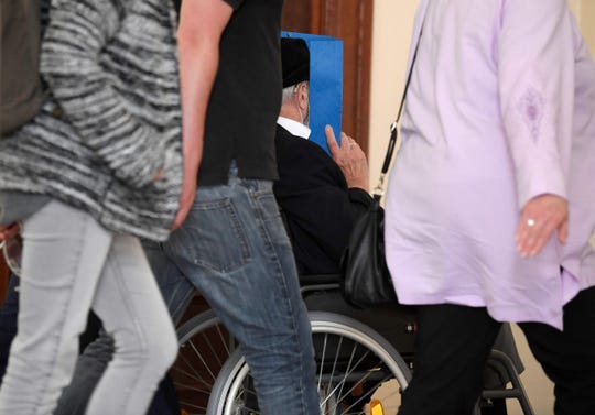 Bruno Dey, a former SS watchman at the Stutthof concentration camp, hides his face behind a folder as he leaves the courtroom on a wheelchair after the verdict in his trial on July 23, 2020, in Hamburg, northern Germany. The 93-year-old former Nazi concentration camp guard was handed a suspended sentence of two years in prison as a court in Hamburg found him guilty of complicity in WWII atrocities. In what could be one of the last such cases of surviving Nazi guards, Bruno Dey was convicted for his role in the killing of 5,230 people when he was a teenage SS tower guard at the Stutthof camp near what was then Danzig, now Gdansk, in Poland.