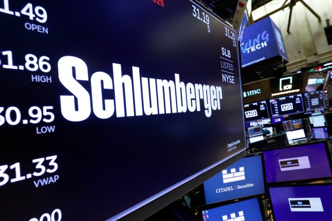 FILE - In this Oct. 8, 2019 file photo, the logo for Schlumberger appears above a trading post on the floor of the New York Stock Exchange.   Schlumberger is cutting more than 21,000 jobs and paying $1.02 billion in severance as declining oil prices amid the coronavirus pandemic push it to slash costs  Schlumberger Ltd. said in a regulatory filing on Friday, July 24, 2020, that vast majority of the severance charge is expected to be paid out during the second half of the year.  (AP Photo/Richard Drew, File)