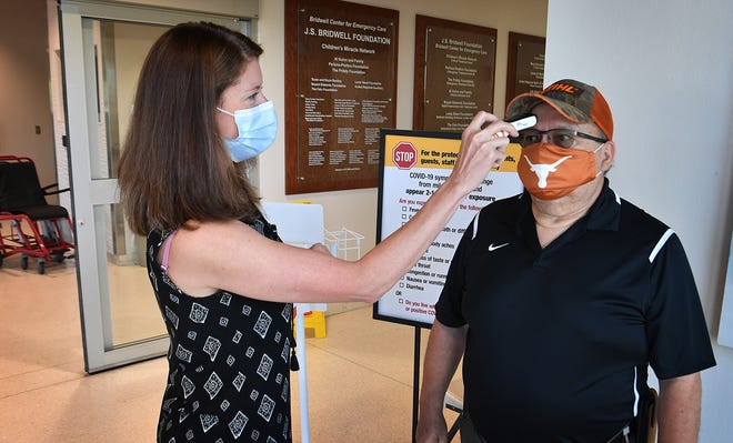 Erica Byers of United Regional checks the temperature of Pete Martinez as he arrives at the hospital's Emergency Room.