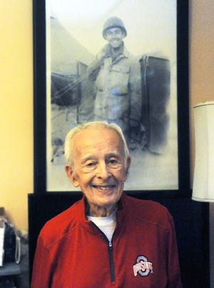 Zanesville resident Joe Pishner poses in front of his Army photo from World War II for a recent story. Pishner passed away on Saturday at the age of 96.