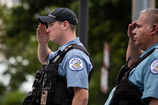 Officers salute outside the Cook County Medical Examiner's Office as an ambulance passes, containing the body of a Chicago Police officer, Tuesday, July 28, 2020, in Chicago.