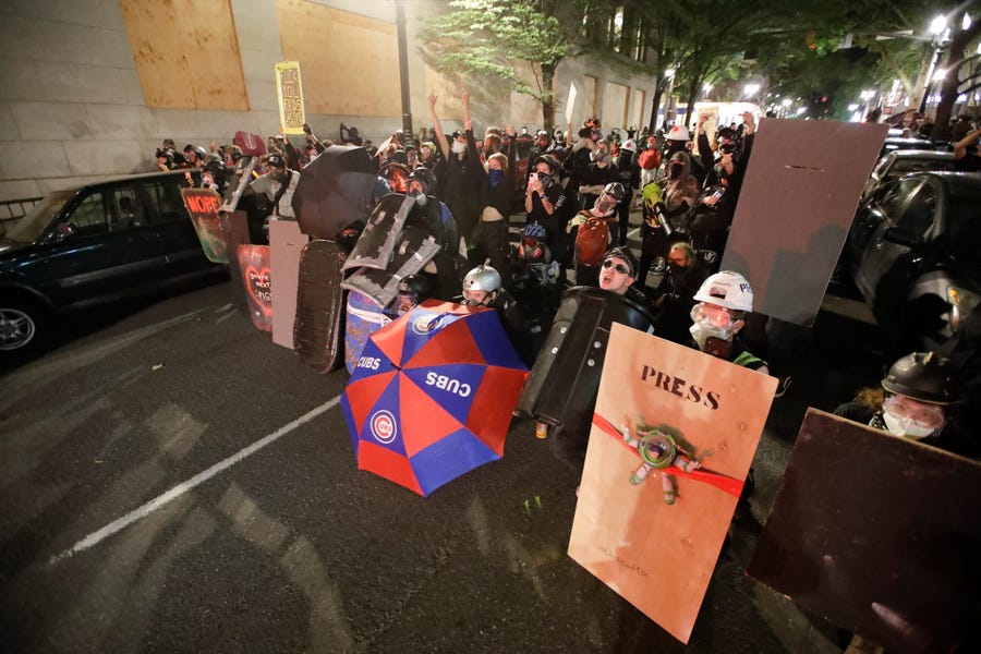 Demonstrators shield themselves from advancing federal officers during a Black Lives Matter protest Tuesday, July 28, 2020, in Portland, Ore. 