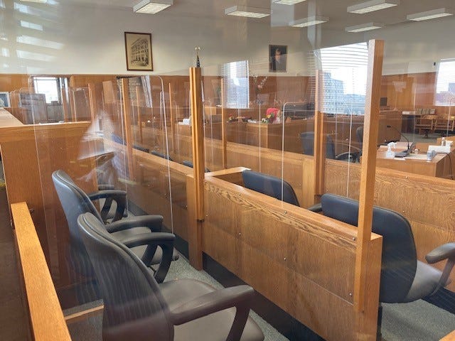 Plexiglass barriers separate each row and seat of the jury box in a Milwaukee County courtroom.