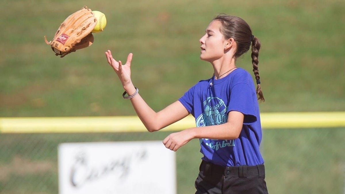 Kendall Kemm, who lost the use of her left arm after undergoing treatment for a brain arteriovenous malformation, gets ready to throw a softball.