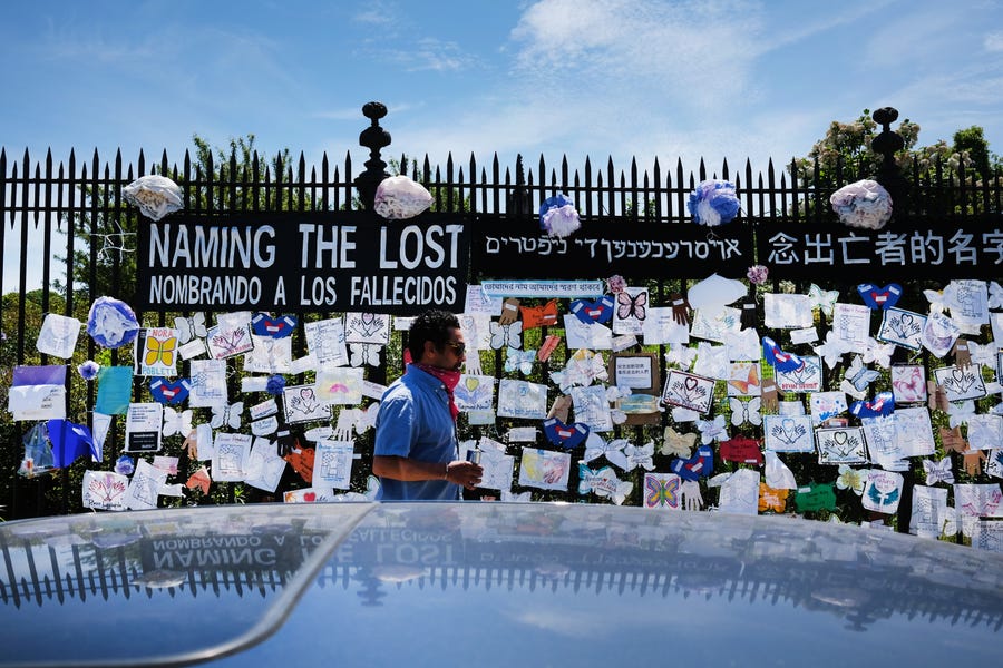 A man walks by a memorial for those who have died from the coronavirus outside Green-Wood Cemetery on May 27, 2020 in the Brooklyn borough of New York City. Green-Wood Cemetery, one of New York's oldest cemeteries, has been the site of hundreds of burials and cremations of COVID-19 victims.