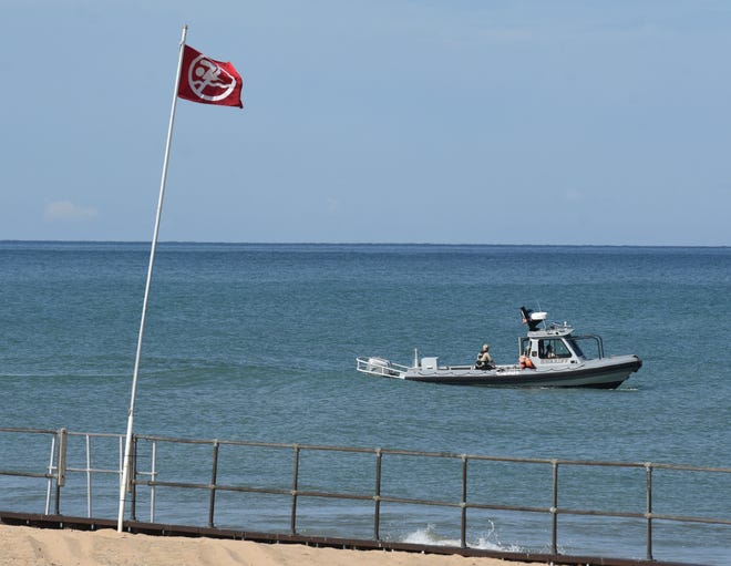 A Berrien County Sheriff Department Marine division boat motors off the beaches at Warren Dunes State Park, in Bridgman, Mich., Friday, July 31, 2020, as rescue crews search for a missing swimmer.
