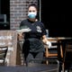 Magda Pleus wears a mask and gloves while carrying an order to a customer in the outdoor dining area at Hinterland Brewery on July 31, 2020, in Ashwaubenon, Wis.