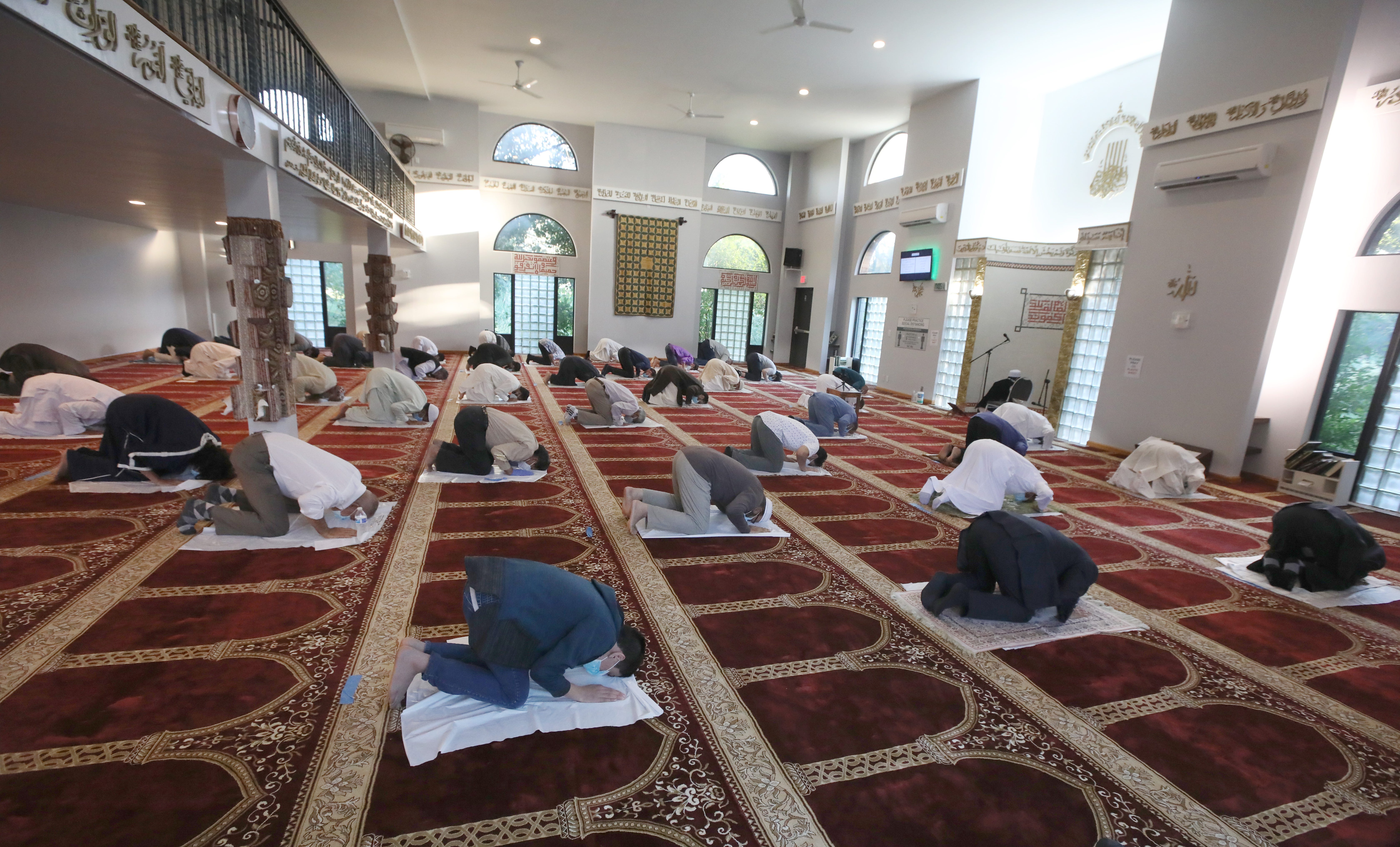 Inside the Islamic Center of Rochester, Rochester-area Muslims pray as they celebrate Eid al-Adha July 31, 2020. Due to coronavirus, the Center took extra precautions, setting up plastic sheets spaced six feet apart all throughout inside the prayer hall.