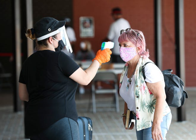 Vero Beach Elementary nurse Liza Colon (left) checks the temperature of Cheryl Denapoli, of Vero Beach, before she enters the Freshman Learning Center hurricane shelter on Saturday, Aug. 1, 2020, in Vero Beach. New temperature scanners that can detect fevers greater than 100.2 will be installed in some county buildings by next week. The scanners also will be used at emergency hurricane shelters.