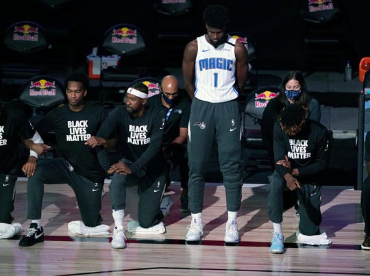 July 31: Magic forward Jonathan Isaac stands as others kneel during the national anthem before playing the Nets.