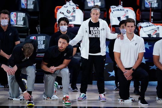 San Antonio Spurs assistant coach Becky Hammon stands beside players as they kneel before a game against the Memphis Grizzlies on Sunday, Aug. 2, 2020, in Lake Buena Vista, Fla.