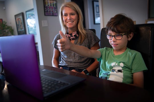 Heather Powell's son, Hawkes, gives a thumbs up as they connect via a laptop and a group chat application to his first grade teacher at Glendale Elementary from their home on the first day of school Aug. 4 in Nashville.