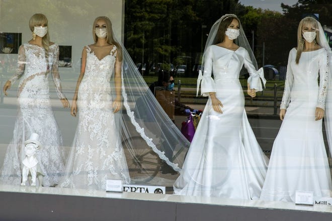 A masked cyclist is reflected in the window of a wedding dress store with mannequins wearing face masks, in Zagreb, Croatia on April 23, 2020. Now that weddings have slowly cranked up under a patchwork of ever-shifting restrictions, horror stories from vendors are rolling in. Many are desperate to work after the coronavirus put an abrupt end to their incomes and feel compelled to put on their masks, grab their cameras and hope for the best. (AP Photo/Darko Bandi)