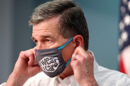 Gov. Roy Cooper prepares to take off his mask to talk during a briefing at the Emergency Operations Center in Raleigh, N.C., Wednesday, August 5, 2020.