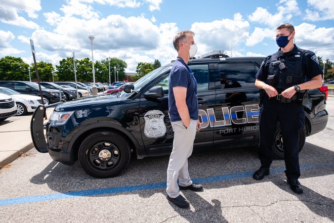 St. Clair County CMH Mobile Crisis Unit Supervisor Bill Slusher, left, talks with Port Huron Police Officer Zach Washkevich Wednesday, Aug. 5, 2020, outside the Municipal Office Center in Port Huron. CMH workers assist local law enforcement on calls that may involve subjects with mental health or substance use problems.