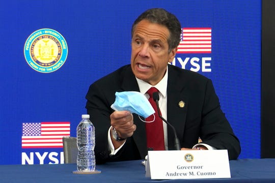 New York Gov, Andrew Cuomo holds his face mask while talking to the media at the New York Stock Exchange, Tuesday, March 26, 2020. Gov. Cuomo rang the opening bell as the trading floor partially reopened during the coronavirus pandemic.