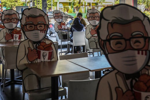 Visitors to a fast-food restaurant share a seat with Colonel Sanders' cutout as an effort to force a physical distancing as a measure to prevent COVID-19 coronavirus spread in Medan, North Sumatra on August 7, 2020.