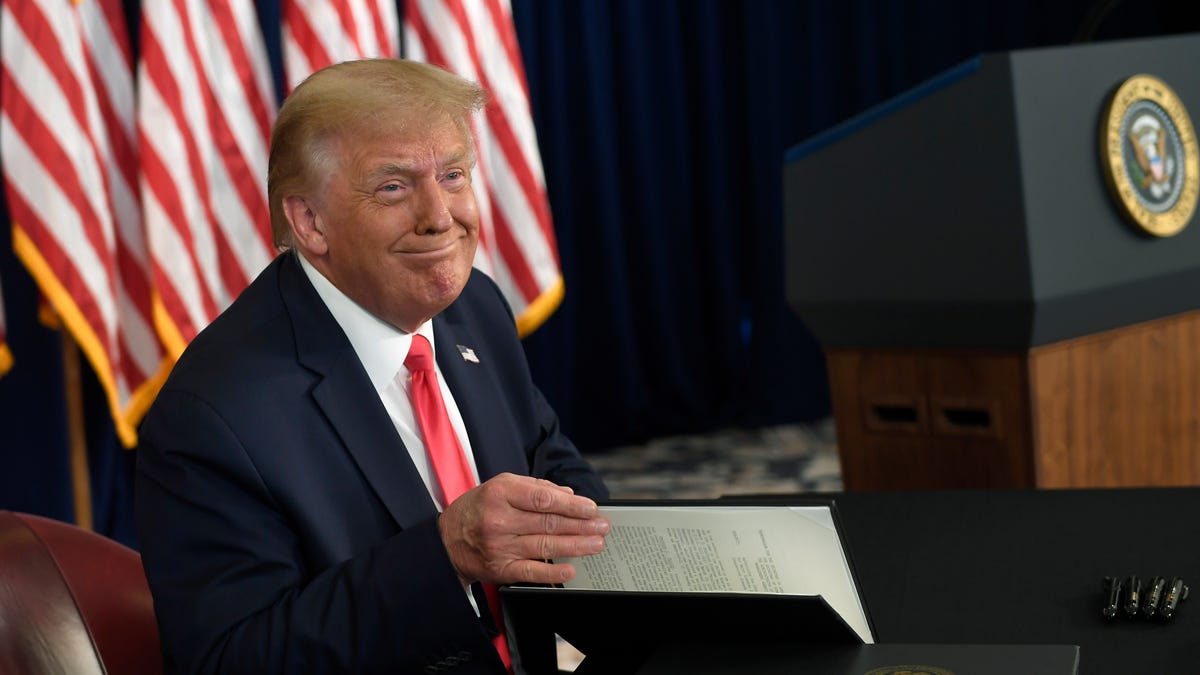 President Donald Trump smiles as he is about to sign four executive orders during a news conference at the Trump National Golf Club in Bedminster, N.J., Saturday, Aug. 8, 2020. (AP Photo/Susan Walsh) ORG XMIT: NJSW109