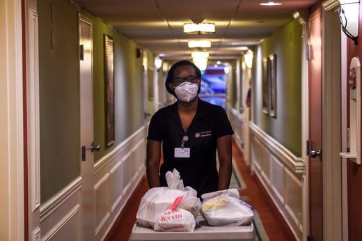 Shanika Williams wears a facemask as she delivers food in John Knox Village, a retirement community in Pompano Beach some 40 miles north of Miami, Fla. on Aug. 7, 2020.  About 900 retirees live in the John Knox Village senior community in Pompano Beach, South Florida. Of these, about 400 have learned to use technology to order food to their apartments, communicate with each other or participate in online social activities.