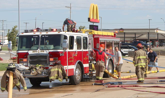 Pratt firefighters roll up and store hoses after putting out a very small fire at Kansas Inn on Aug. 7 after a welder caught wood on fire underneath siding at an outside stairwell.