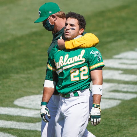 Ramon Laureano is held by an Oakland Athletics sta