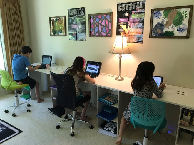 From left to right: Alexander, Sophia and Charlotte Hess work on their assignments on Aug. 11, Muncie Community School's first day back.
