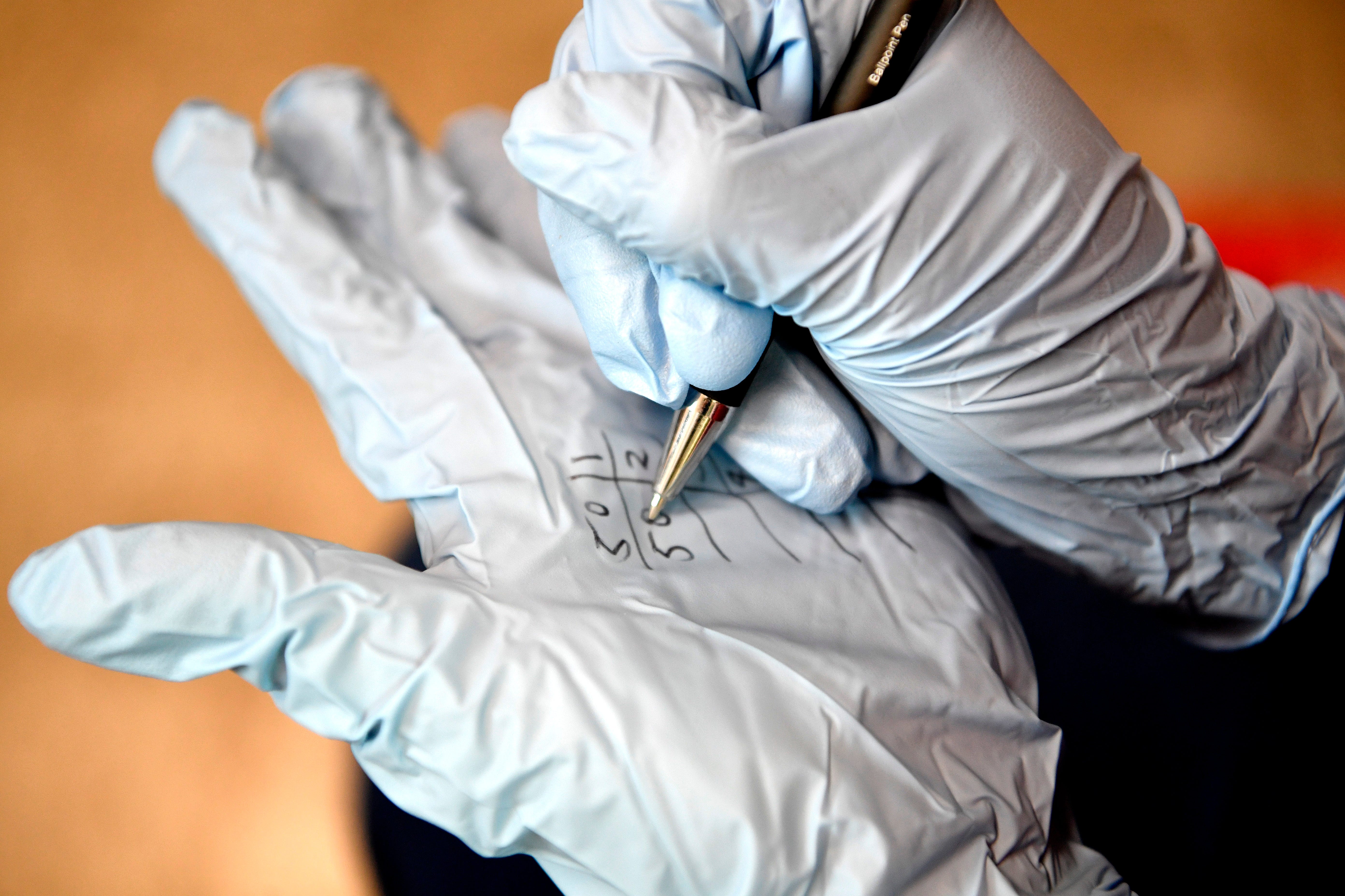Amber DuVentre writes the number of test kits she counted Tuesday morning on her glove in Nashville, Tenn. Tuesday, Aug. 11, 2020