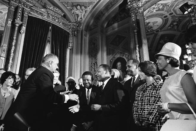 President Lyndon Baines Johnson moves to shake hands with Dr. Martin Luther King after signing the Voting Rights Act in the Rotunda of the US Capitol in 1965.