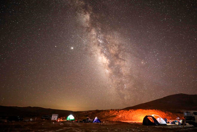 A Perseid meteor streaks across the sky above a camping site at the Negev desert near the city of Mitzpe Ramon on Aug. 11, 2020 during the Perseids meteor shower.