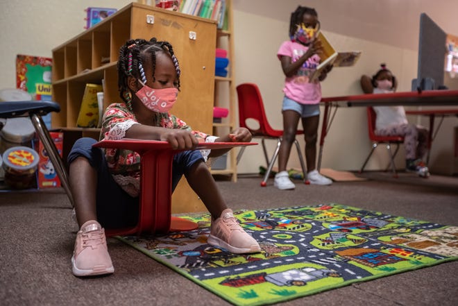 Alonah Montgomery sits on the floor socially distanced from other children while going over a lesson as Laiyah Singletery reads at Pippen Palace Childcare Academy on Detroit's west side on August 13, 2020.