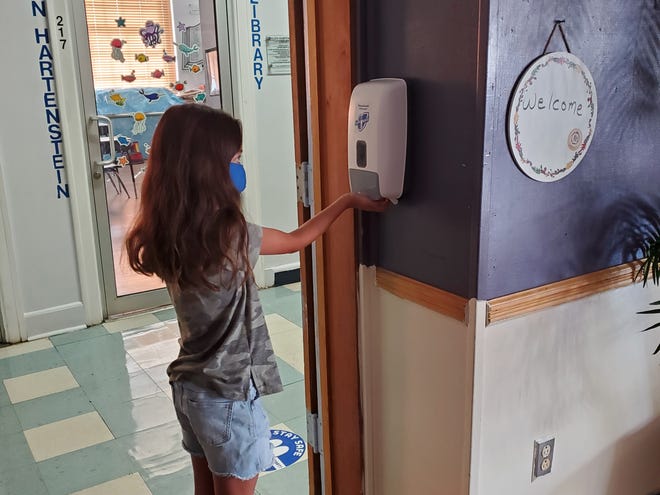 Molly Goldfarb, a student at Abrams Hebrew Academy in Yardley, checks out one of many hand sanitizing dispensers she will be using when school starts on Tuesday. [photo: COURTESY ABRAMS HEBREW ACADEMY]