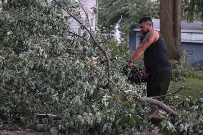 Tyrone Gomez sawing down tree limbs that fell following the storm that passed through Perry Monday, Aug. 10.