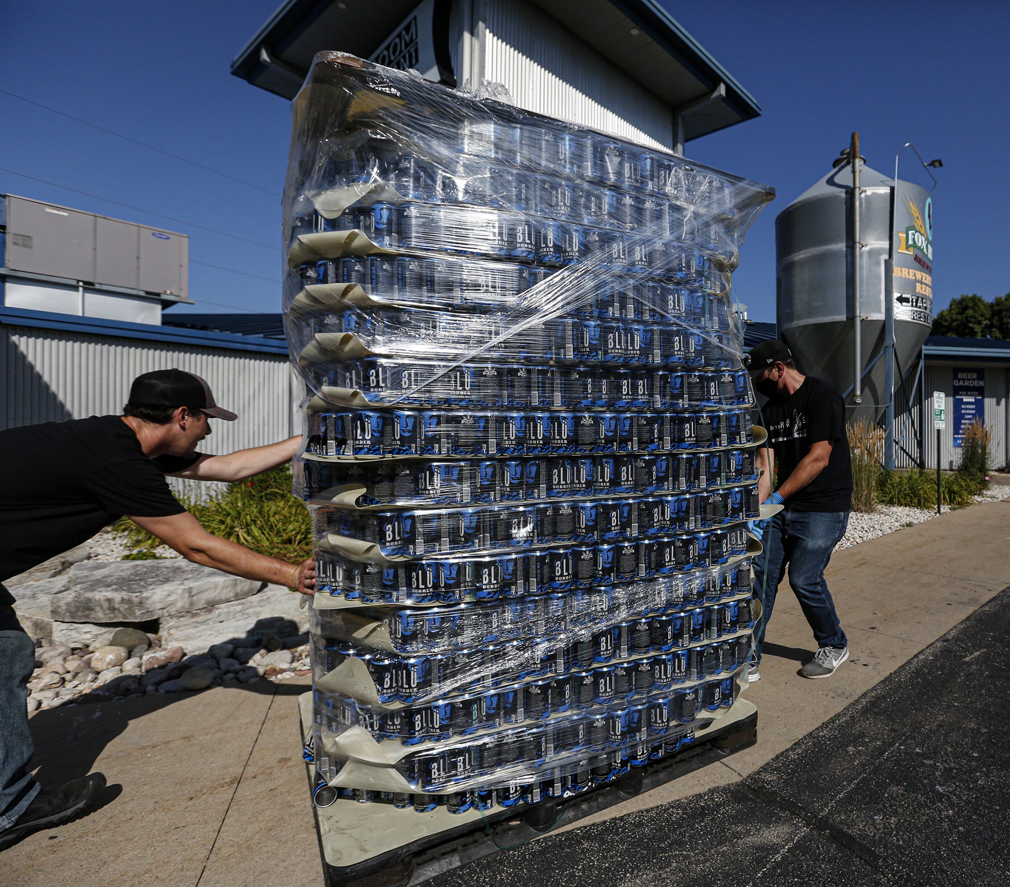 Tyler Severinsen of Neenah and Matt Berger of Appleton bring a stack of empty Blu Bobber beer cans to Fox River Brewing Co. in Oshkosh.