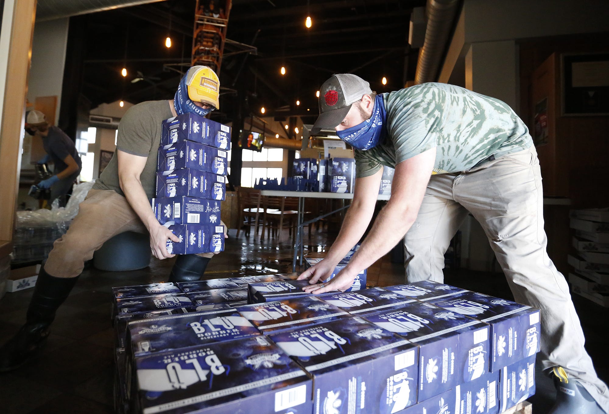 Andrew Roth and Patrick McHugh of Oshkosh stack cases of cans of Blu Bobber beer at Fox River Brewing Co. in Oshkosh.