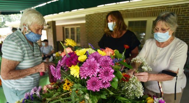 Franciscan Manor residents Eleanor Smolar, left, and Avis Watt, right, work with Melissa Berg, marketing director at Franciscan Manor, to create floral bouquets.