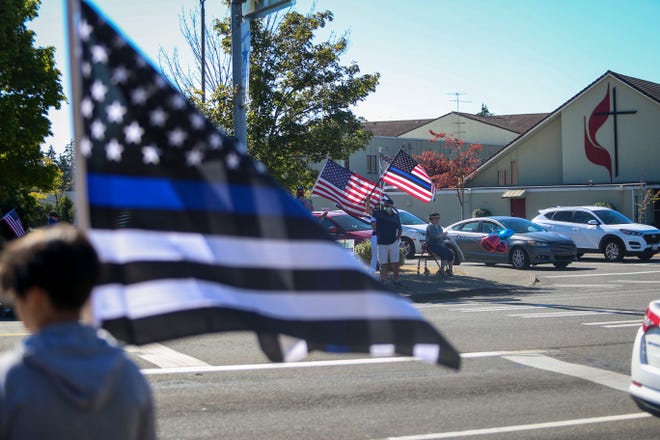 A crowd gathered on the street and corners near Kitsap Mall in Silverdale on Saturday to show support for law enforcement. They held flags and chanted "back the blue."