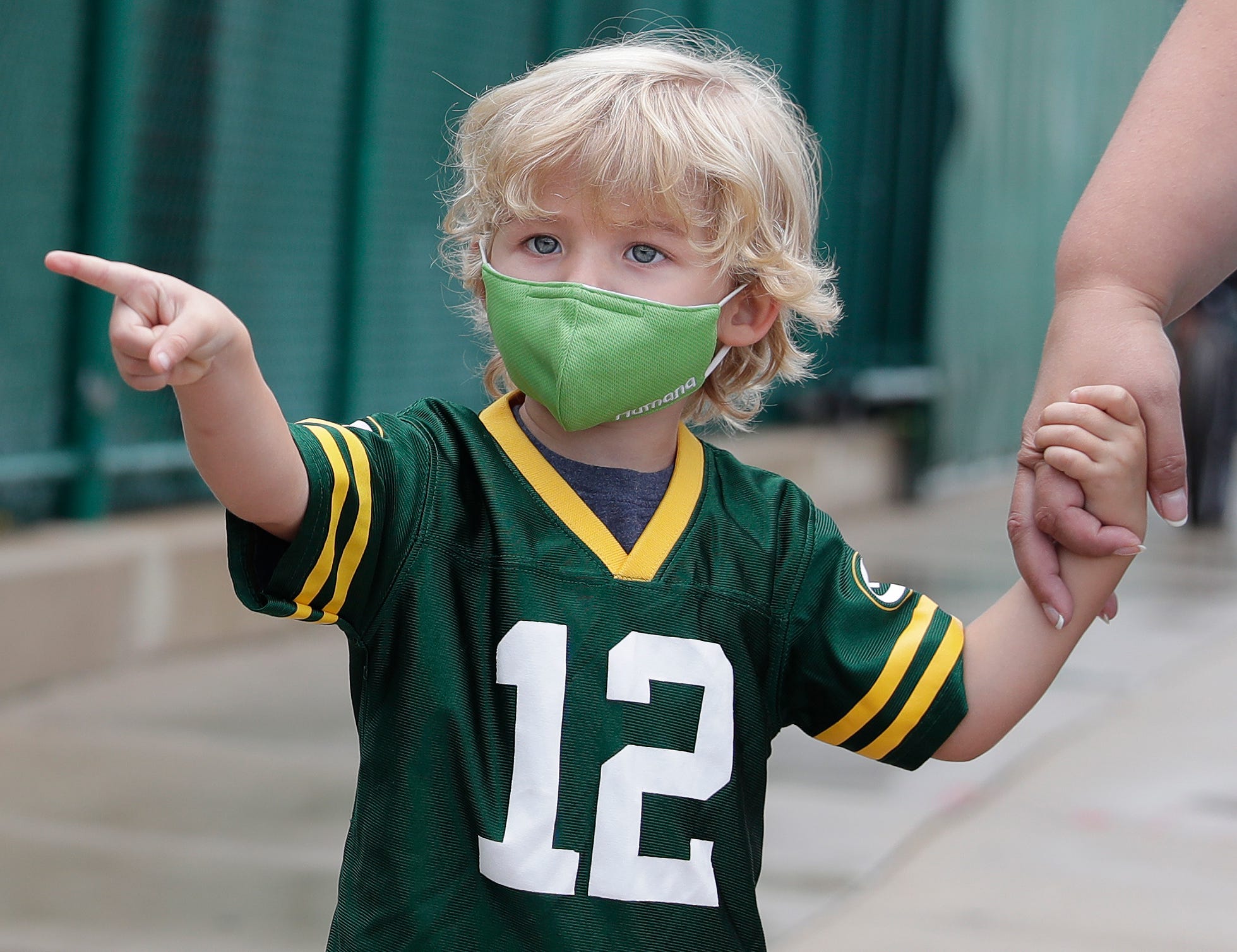 Keegan DeMuth, 3, of Appleton points to Green Bay Packers players at they walk to practice on Aug. 15, 2020, in Ashwaubenon, Wis. The team began its first practice of training camp at Ray Nitschke Field, but with no public viewing due to the coronavirus pandemic, only a few fans visited the area.