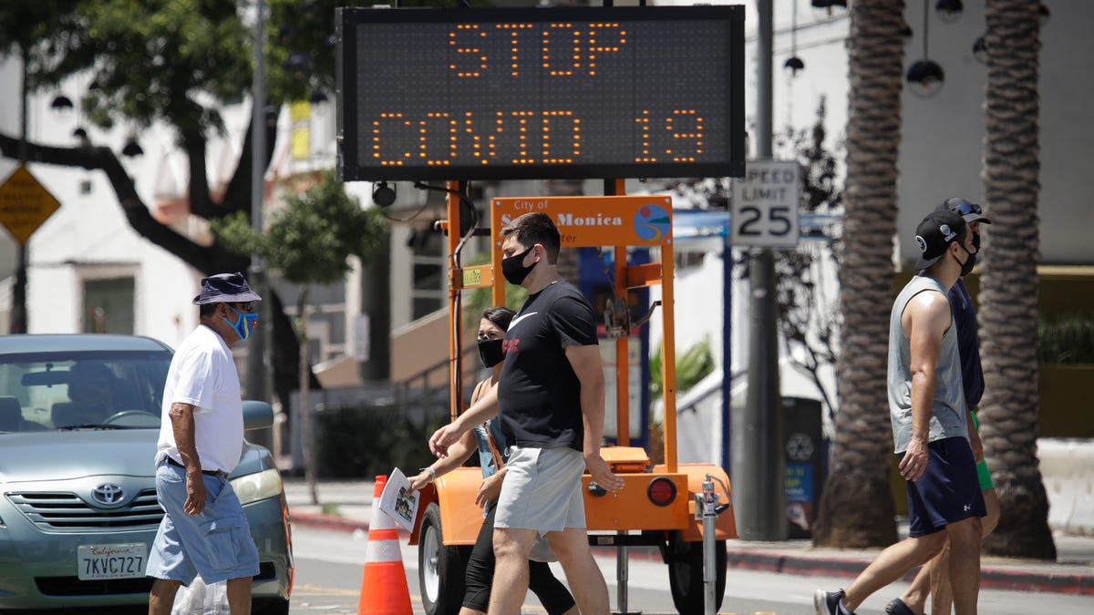 Pedestrians wear masks as they cross a street amid the coronavirus pandemic in Santa Monica, California.