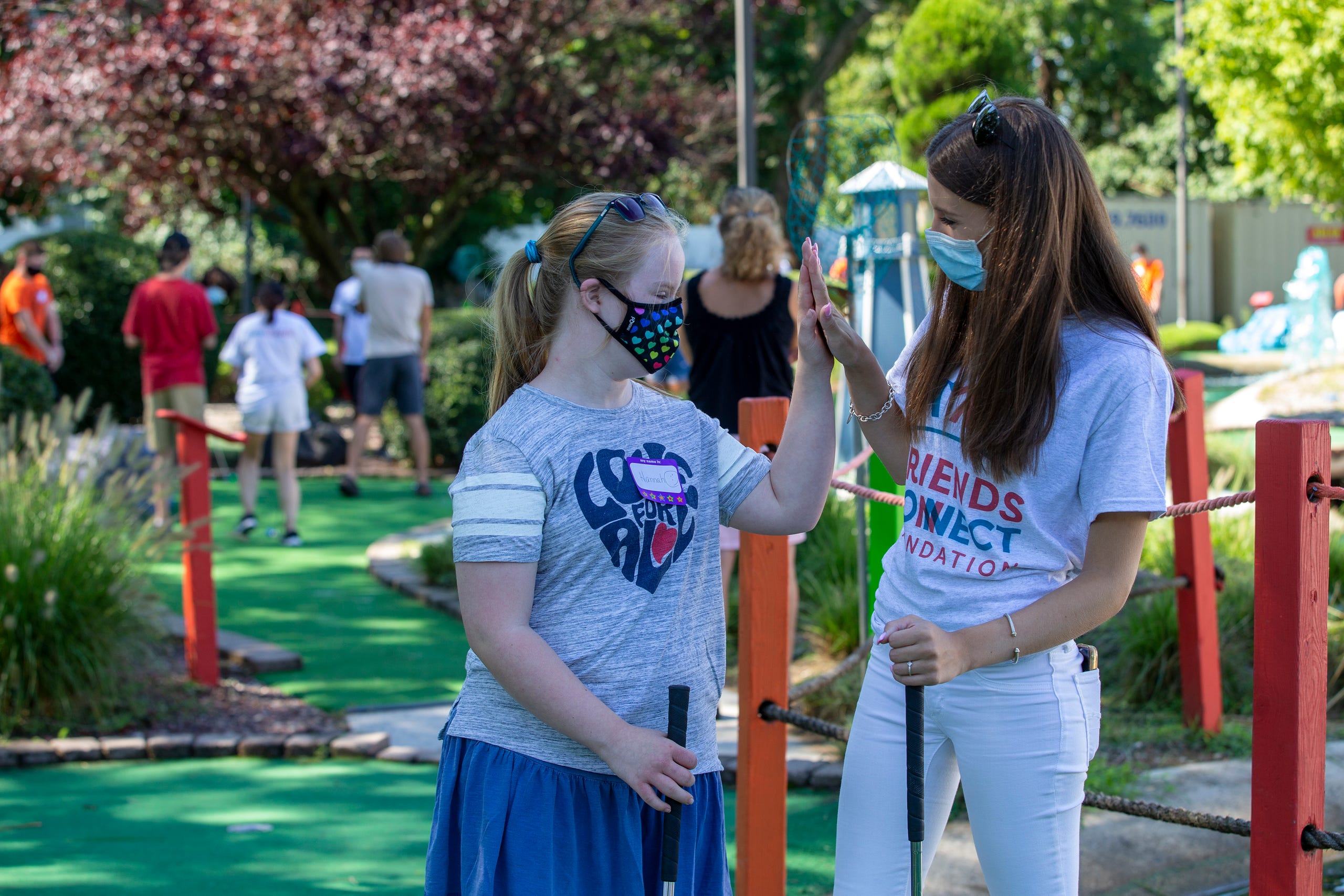 (right) Sophia Ziajski, 19, of Middletown, who runs the nonprofit Friends Connect Foundation, high fives (left) Hannah Piasecki, 13, of Middletown as members of the Middletown North boys soccer team play mini-golf with a group of special-needs kids as part of Friends Connect Foundation at TST BBQ & Mini Golf in Middletown, NJ Tuesday, August 18, 2020.