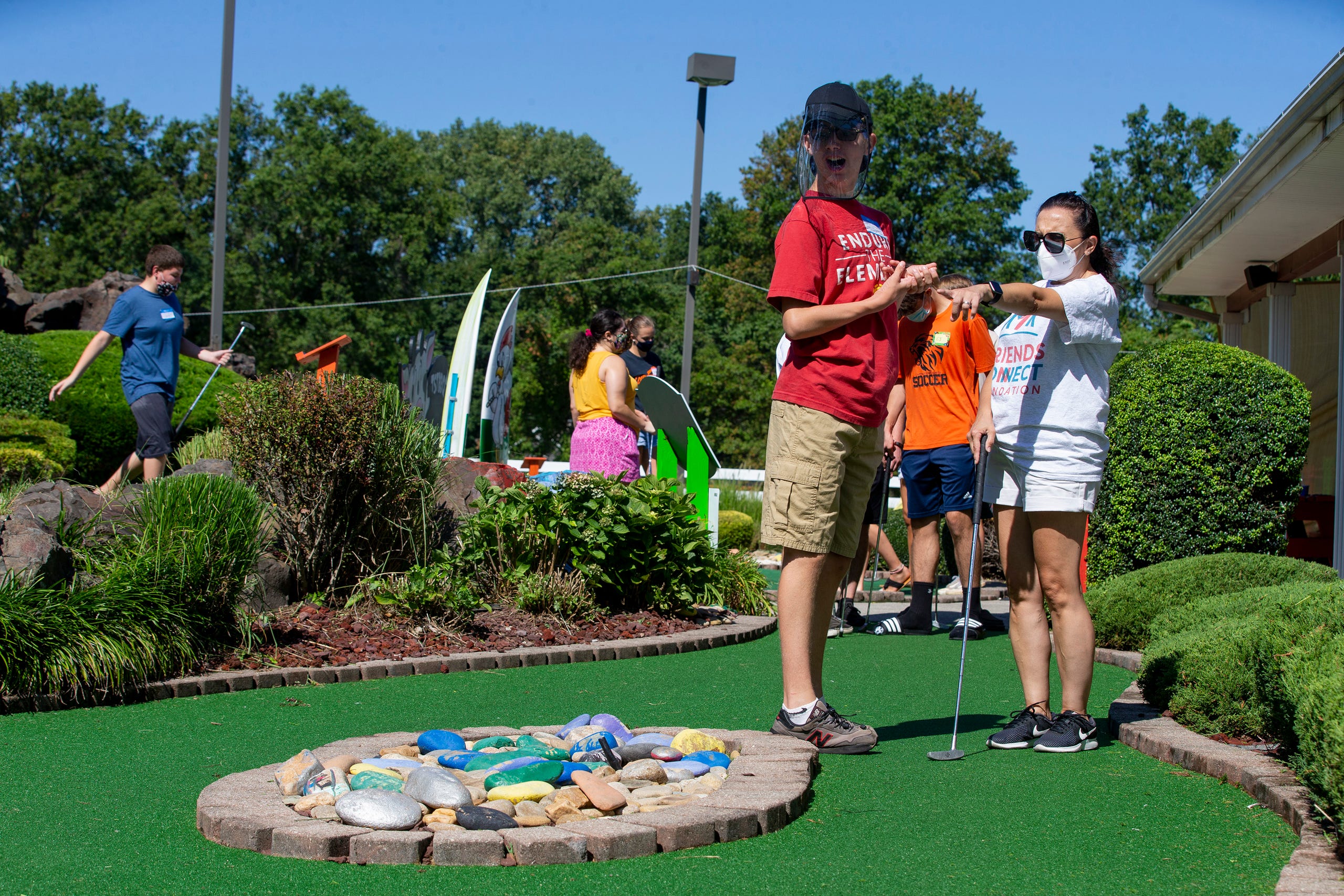 (right) Andrea Ziajski of Middletown, a volunteer with the Friends Connect Foundation, teaches (left) Matty Driscoll, 16, of Fair Haven to golf as members of the Middletown North boys soccer team play mini-golf with a group of special-needs kids as part of Friends Connect Foundation at TST BBQ & Mini Golf in Middletown, NJ Tuesday, August 18, 2020.