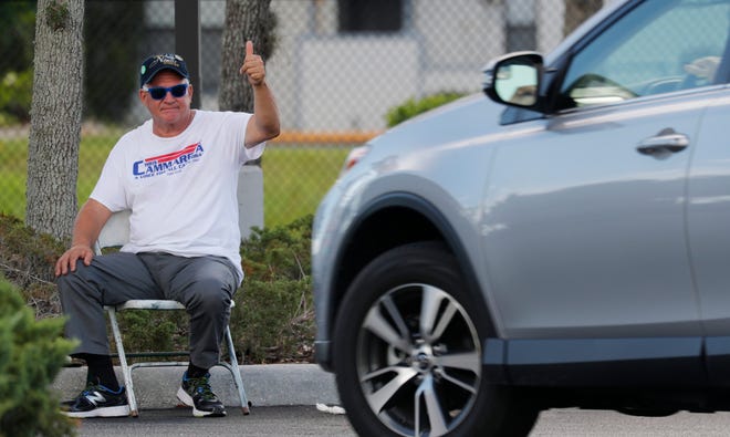Chris Cammarota, a candidate for Cape Coral City Council's District 3 waves to potential voters on election day Tuesday, August 18, 2020, at the Cape Coral library voting precinct.